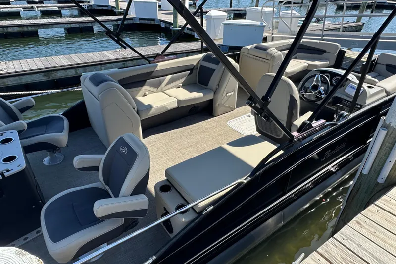 Slide: The Image of 2022 Barletta Cabrio 22CC pontoon boat interior with plush seating at a marina. - 14