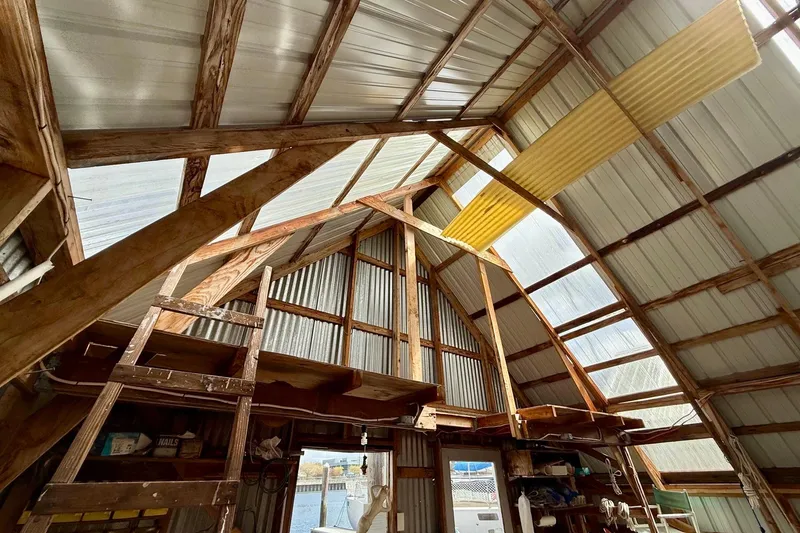 Slide: The Image of Interior of a 1990 BoatHouse 19x43 with wooden beams and corrugated metal roof. - 4