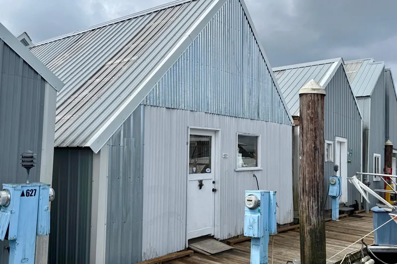 Slide: The Image of Boathouse 19x43 from 1990 with metal siding and dockside utility meters. - 9