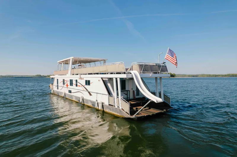 Slide: The Image of Houseboat Horizon 18x85 (2009) with slide and flag on a serene lake. - 3
