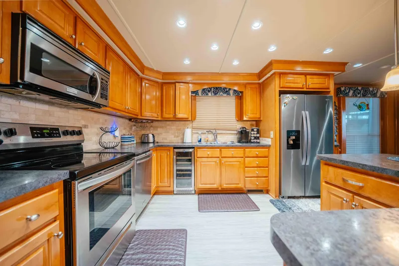 Slide: The Image of Spacious kitchen with wooden cabinets, stainless steel appliances, and modern lighting in a 2009 Horizon 18x85. - 34