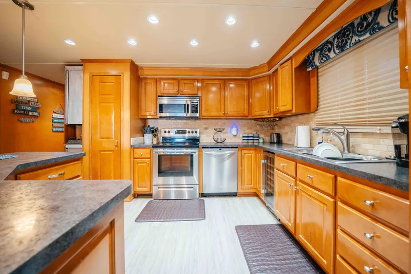 Slide: The Image of Spacious kitchen with wooden cabinets, stainless steel appliances, and modern lighting in a 2009 Horizon 18x85. - 35