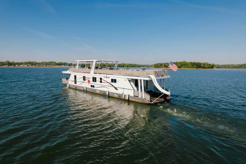 Slide: The Image of Houseboat Horizon 18x85 (2009) cruising on a serene lake with an American flag. - 8