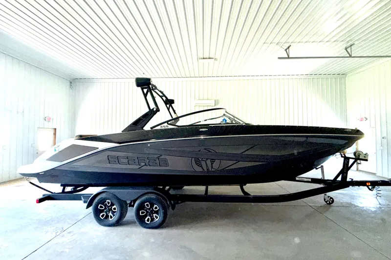Slide: The Image of 2023 Scarab 255 ID boat in a garage, sleek black design on trailer. - 3