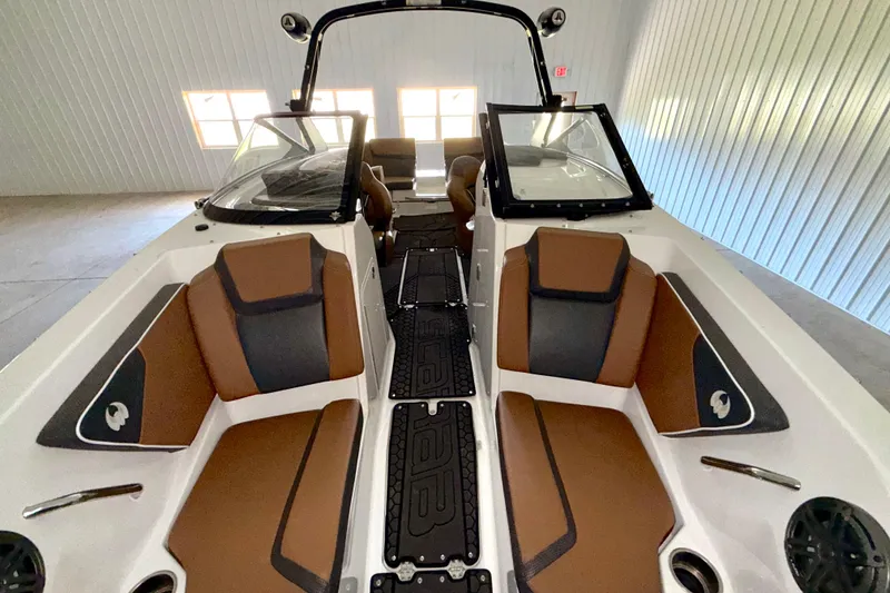 Slide: The Image of 2023 Scarab 255 ID boat interior with brown and black seating in a garage. - 6