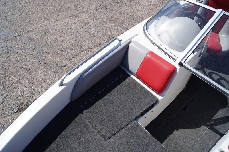 Slide: The Image of 2002 Skeeter SL 210 boat interior with red and gray seating, windshield, and carpeted flooring. - 9