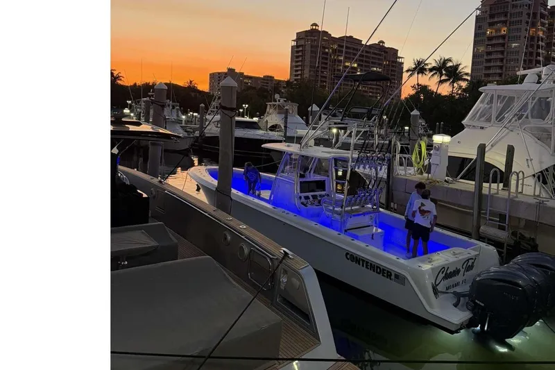 Slide: The Image of 2024 Contender 39 ST boat docked at sunset with blue interior lighting. - 10