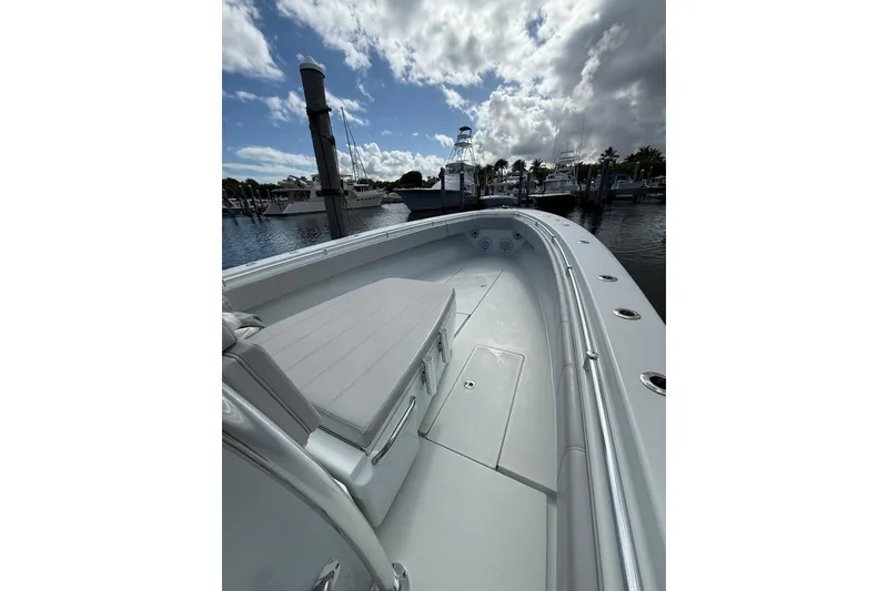 Slide: The Image of 2024 Contender 39 ST boat docked, showcasing sleek design and spacious deck under a cloudy sky. - 13