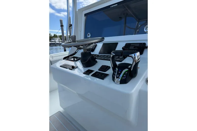 Slide: The Image of 2024 Contender 39 ST boat helm with steering wheel and controls, dockside view. - 17
