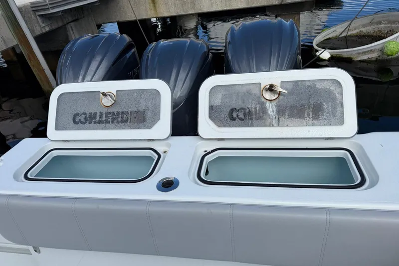 Slide: The Image of 2024 Contender 39 ST boat with open storage compartments and triple outboard engines. - 25