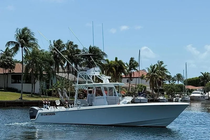 Slide: The Image of 2024 Contender 39 ST boat cruising near palm trees and waterfront homes. - 7