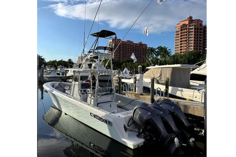 Slide: The Image of 2024 Contender 39 ST boat docked at marina with clear sky and buildings in background. - 9