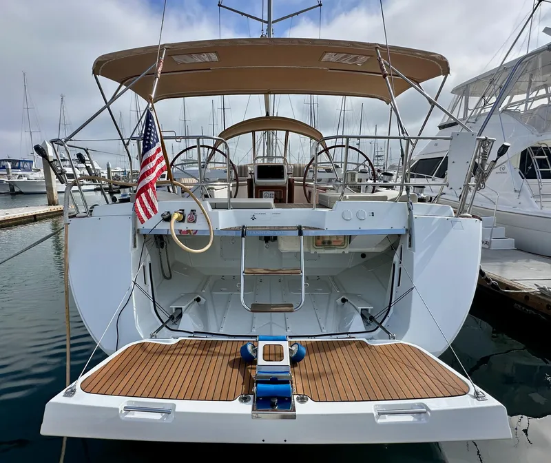 Slide: The Image of 2014 Jeanneau 57 yacht with dual steering wheels and American flag, docked at marina. - 12