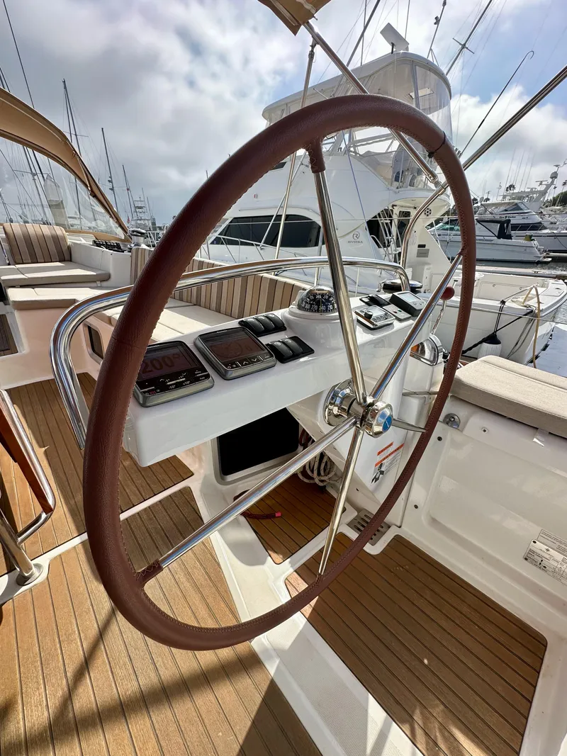 Slide: The Image of Jeanneau 57 yacht helm, 2014 model, featuring a sleek wooden steering wheel and modern navigation instruments. - 31