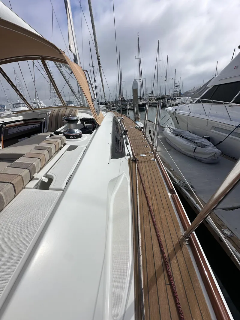 Slide: The Image of 2014 Jeanneau 57 yacht docked at marina, showcasing sleek deck design and luxurious seating. - 38