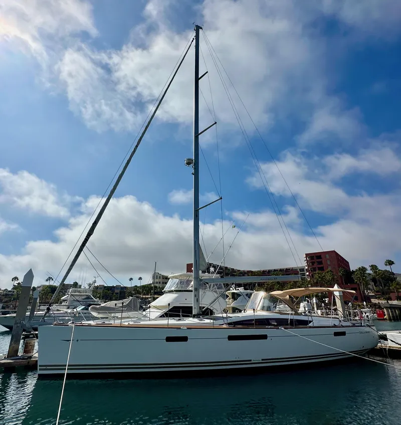 Slide: The Image of 2014 Jeanneau 57 sailboat docked at a marina under a partly cloudy sky. - 9