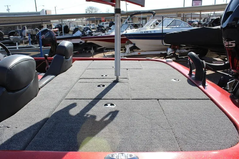 Slide: The Image of 2018 Skeeter ZX225 boat interior with carpeted deck and seating, displayed at a marina. - 15