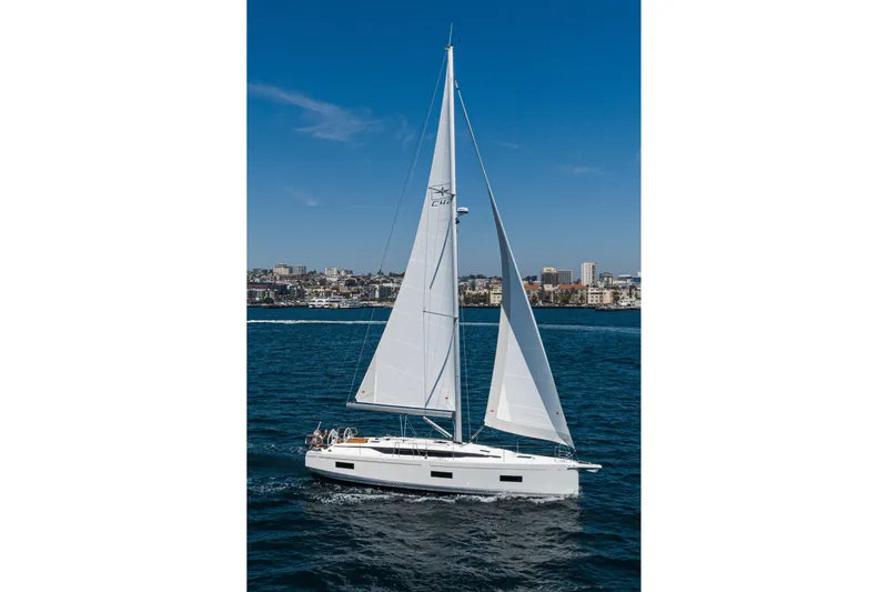 Slide: The Image of 2023 Bavaria C42 sailboat cruising on blue ocean with city skyline in background. - 12