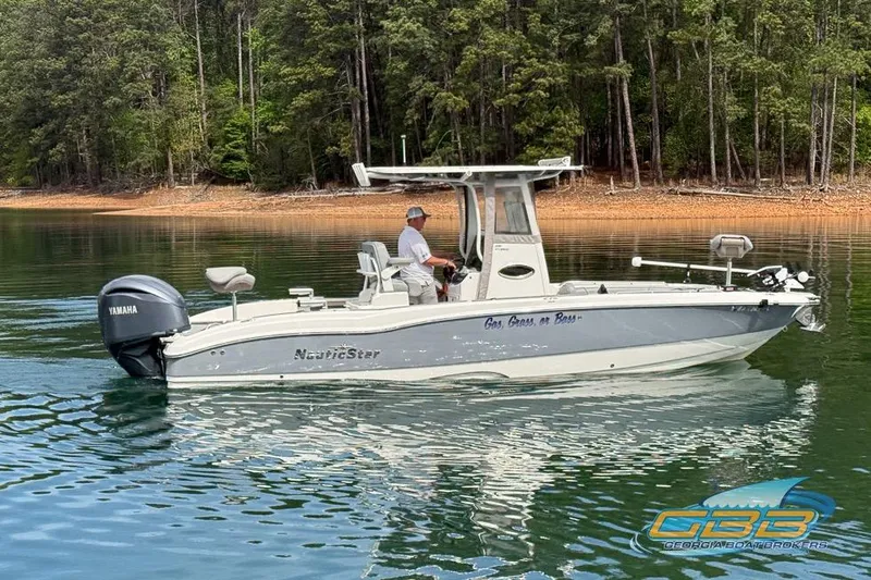 The Image of 2022 NauticStar 251 Hybrid boat on calm lake with forested shoreline. - 0