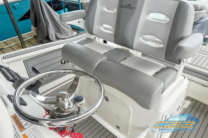 Slide: The Image of 2022 NauticStar 251 Hybrid boat interior with steering wheel and cushioned seating. - 11