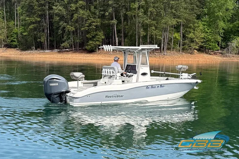 Slide: The Image of 2022 NauticStar 251 Hybrid boat on calm lake with Yamaha motor, surrounded by trees. - 14