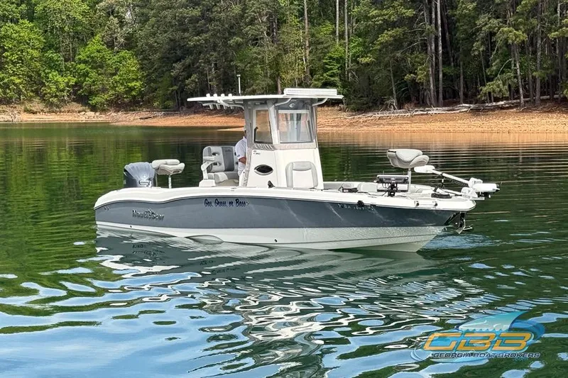 Slide: The Image of 2022 NauticStar 251 Hybrid boat on calm lake with forested shoreline. - 15