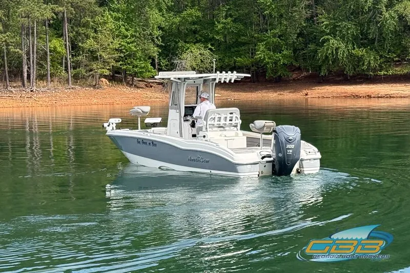 Slide: The Image of 2022 NauticStar 251 Hybrid boat on a calm lake with wooded shoreline. - 16