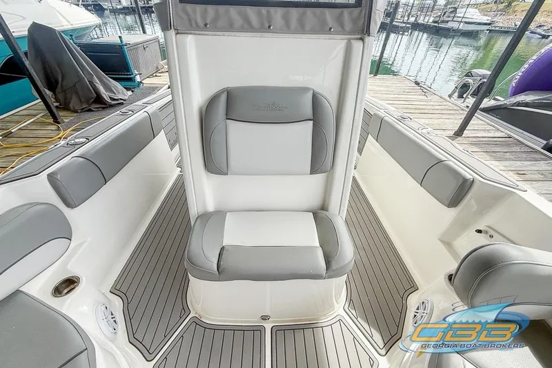 Slide: The Image of 2022 NauticStar 251 Hybrid boat interior with gray seating and deck at a marina. - 22