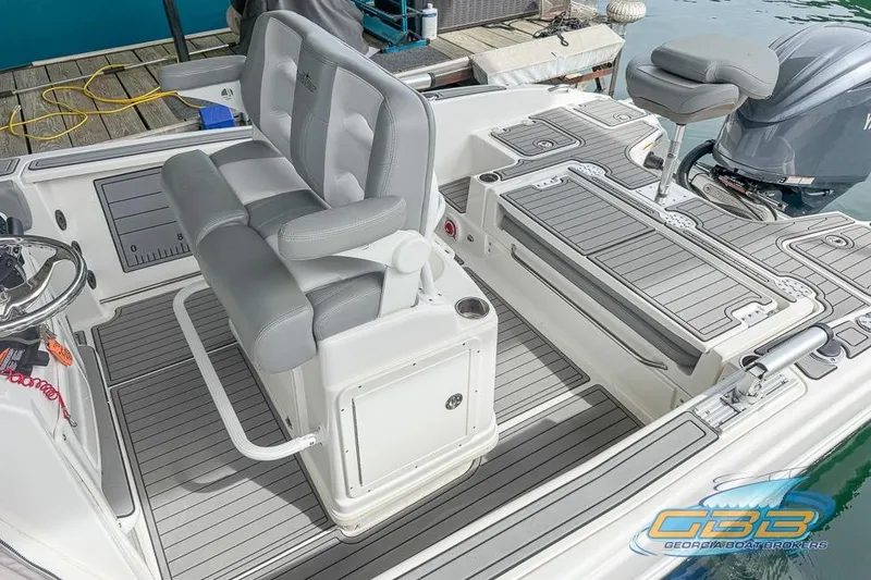 Slide: The Image of 2022 NauticStar 251 Hybrid boat interior with gray seating and deck, docked by water. - 5