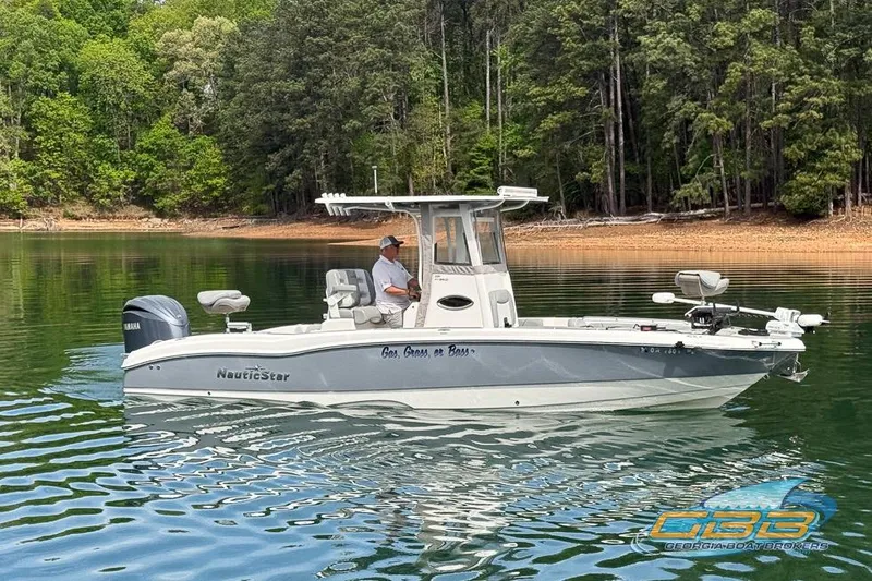 Slide: The Image of 2022 NauticStar 251 Hybrid boat on a calm lake with forested shoreline. - 8