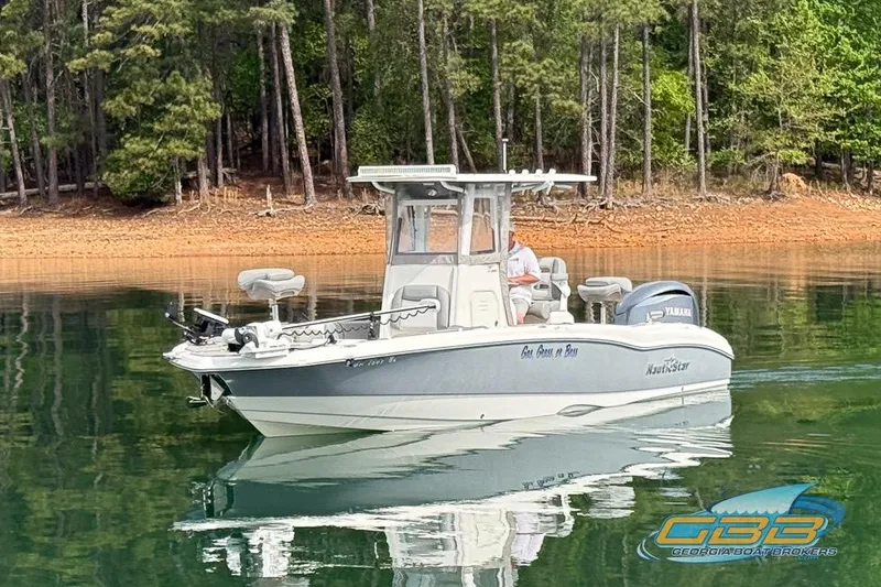 Slide: The Image of 2022 NauticStar 251 Hybrid boat on calm lake with forested shoreline. - 9