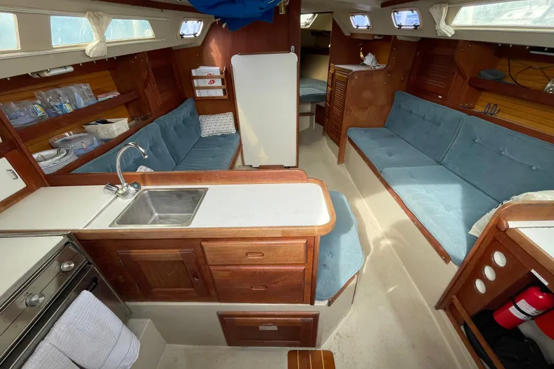 Slide: The Image of Interior of a 1989 Catalina 30 sailboat with blue seating and wooden cabinetry. - 12