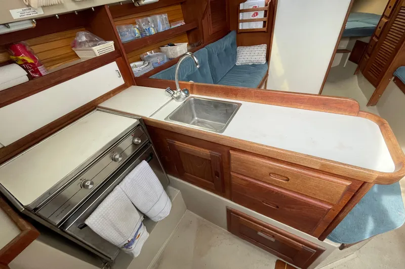 Slide: The Image of 1989 Catalina 30 yacht interior kitchen with sink, stove, and wooden cabinetry. - 13