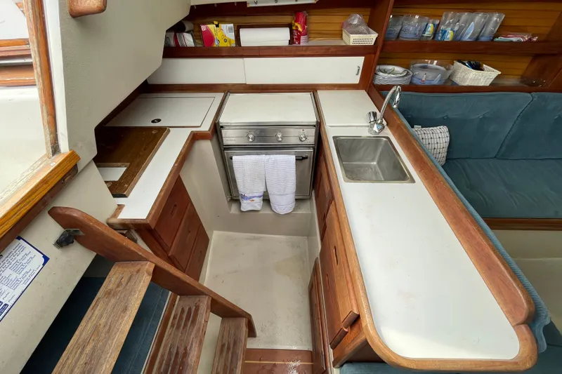 Slide: The Image of Interior of 1989 Catalina 30 sailboat kitchen with stove, sink, and wooden cabinetry. - 14