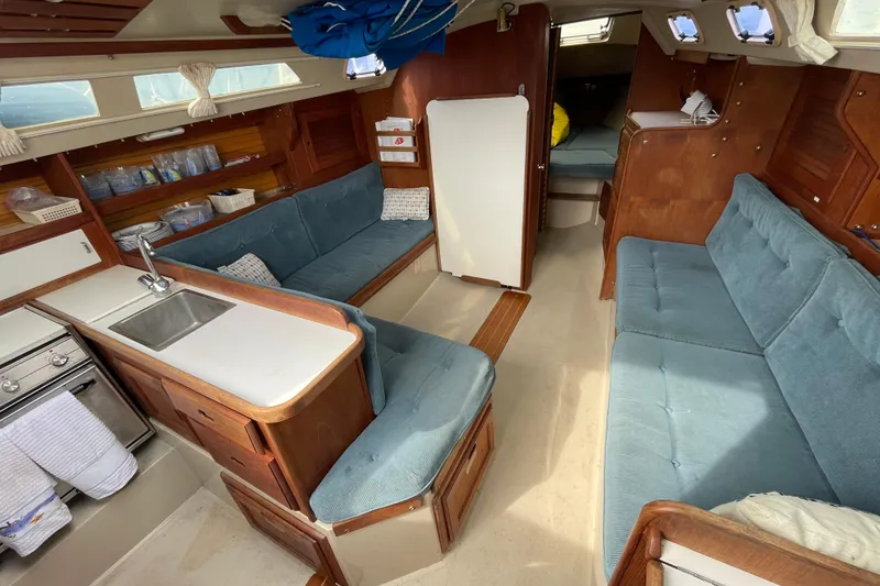 Slide: The Image of Interior of a 1989 Catalina 30 sailboat with blue seating and wooden cabinetry. - 16