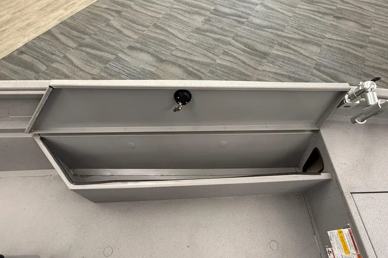 Slide: The Image of 2020 Alumacraft 20 Bay boat storage compartment with open lid and lock mechanism. - 36