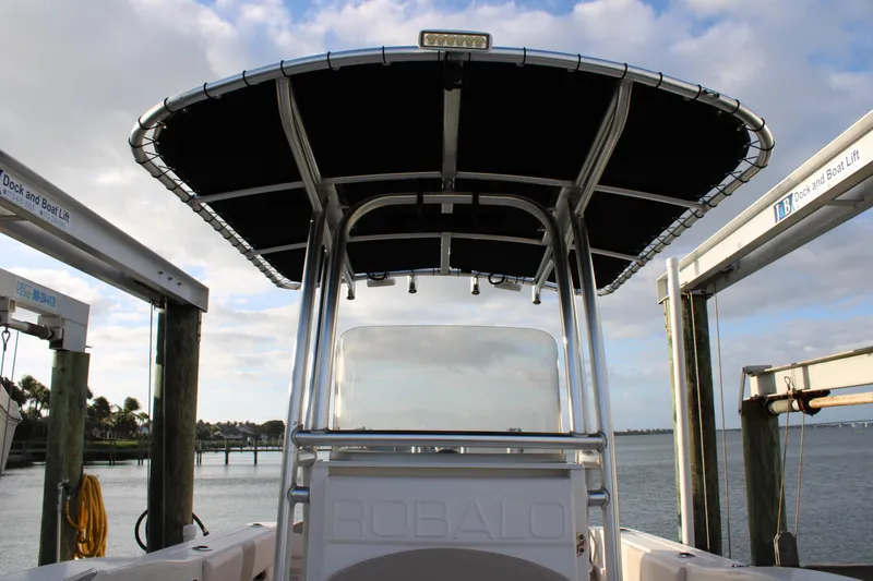 Slide: The Image of 2017 Robalo R200 Center Console boat docked, featuring a sturdy T-top and scenic waterfront view. - 22