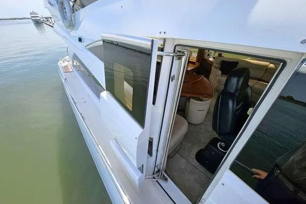 Slide: The Image of 2005 Sunseeker Manhattan 66 yacht, side view with open cabin door, docked on calm water. - 21