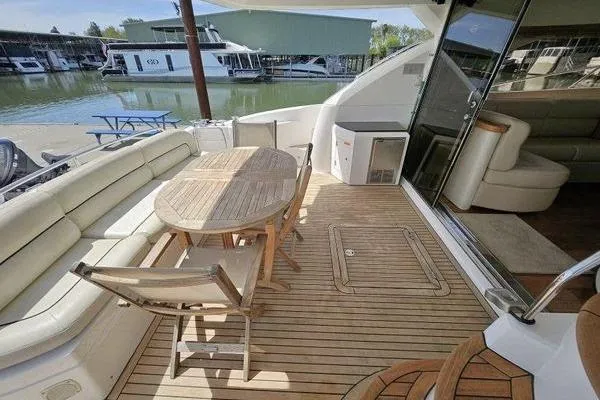 Slide: The Image of Sunseeker Manhattan 66 yacht deck with wooden table and seating, docked at marina. - 6