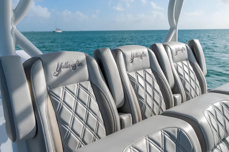 Slide: The Image of 2024 Yellowfin 39 Offshore boat seats with diamond stitching, ocean view in background. - 19