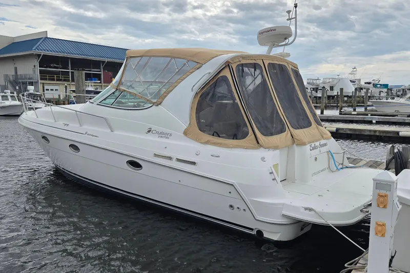 The Image of 2002 Cruisers Yachts 3372 Express docked at marina, featuring tan canopy and sleek design. - 0