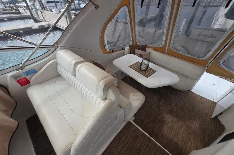 Slide: The Image of Interior of 2002 Cruisers Yachts 3372 Express with white seating and table, dockside view. - 9
