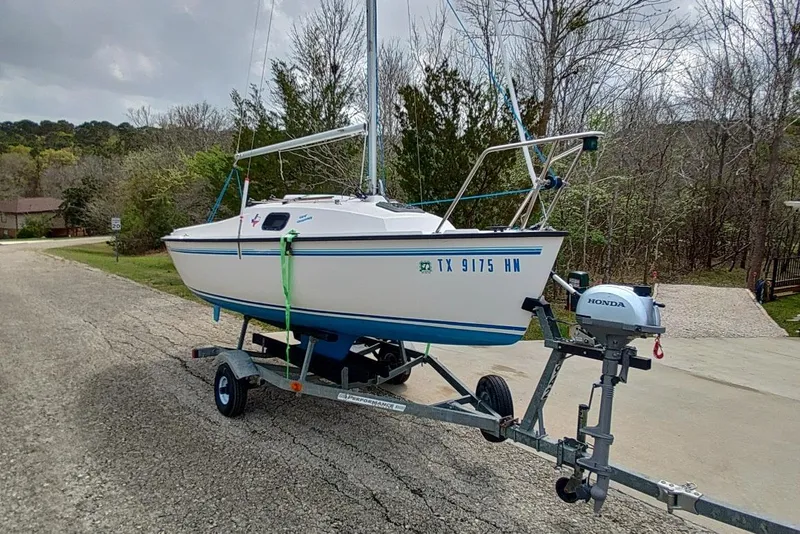 Slide: The Image of 1996 Precision 165 sailboat on trailer with Honda outboard motor, parked on a rural road. - 21