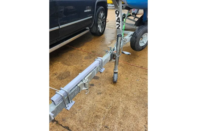 Slide: The Image of Trailer hitch with number 942, parked beside a black vehicle on wet pavement. - 7