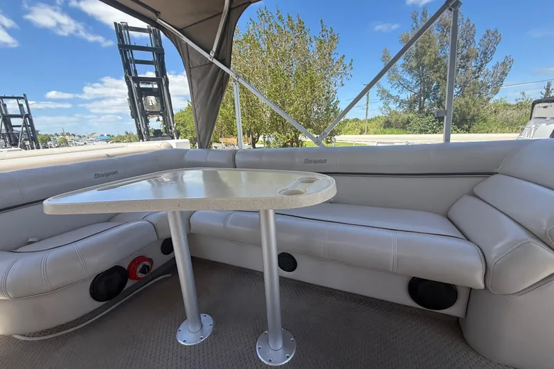 Slide: The Image of Interior of 2003 Godfrey 2200 RE boat with seating and table under canopy. - 13