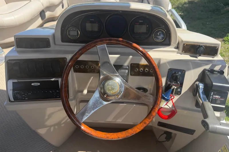 Slide: The Image of Steering console of a 2003 Godfrey 2200 RE boat with wooden wheel and Yamaha controls. - 23