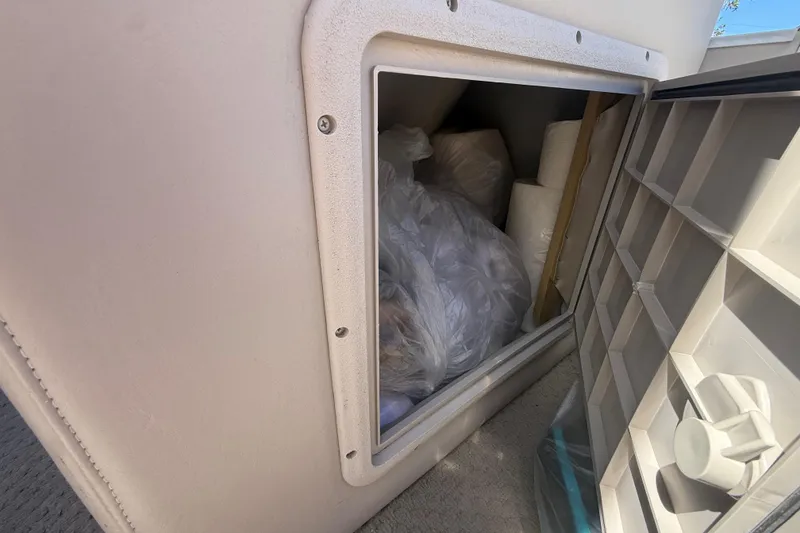 Slide: The Image of Storage compartment on a 2003 Godfrey 2200 RE boat, filled with bags and supplies. - 34