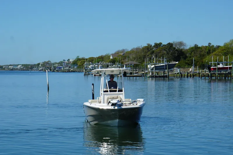 Slide: The Image of 2016 NauticStar 231 Coastal boat cruising on a calm waterway near docks. - 16