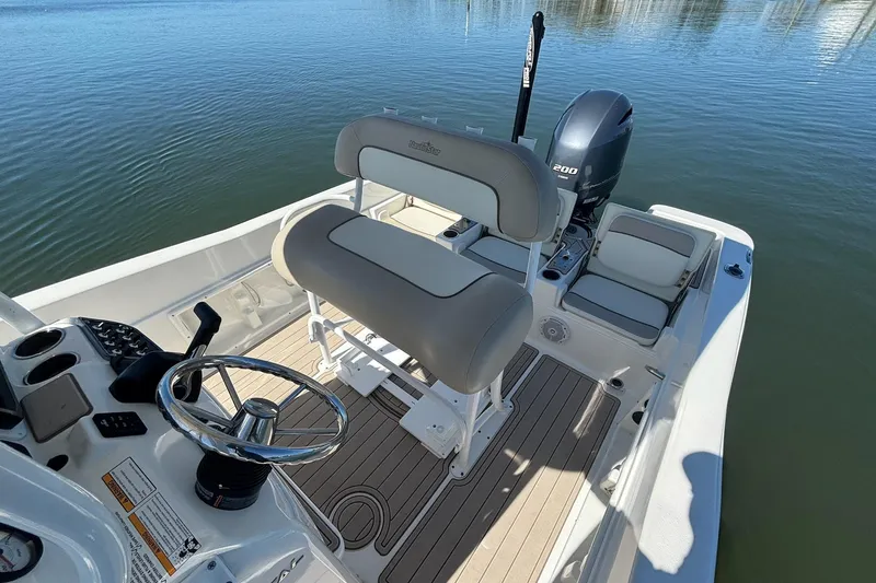 Slide: The Image of 2016 NauticStar 231 Coastal boat interior with seating and controls on calm water. - 19