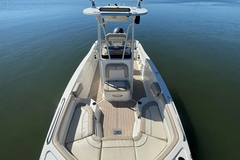 Slide: The Image of 2016 NauticStar 231 Coastal boat on calm water, showcasing spacious deck and seating. - 6